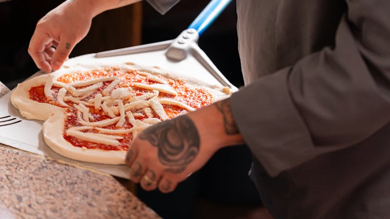 Chef hand-stretching fresh pizza dough